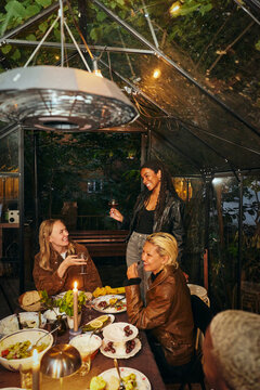 High angle view of smiling young woman giving toasting speech at social gathering dinner party in conservatory