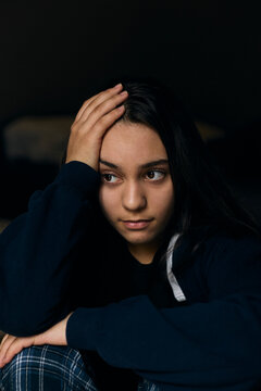 Depressed teenage girl with holding her head while sitting at home