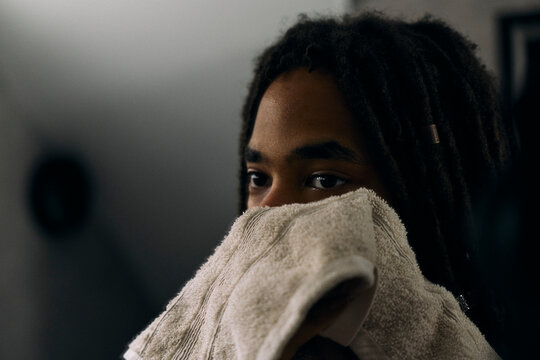 Close-up shot of young man wiping his face with towel