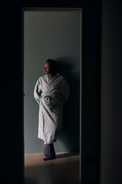 Full length of woman leaning on wall seen through doorway