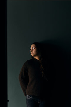 Teenage girl looking away while standing against wall