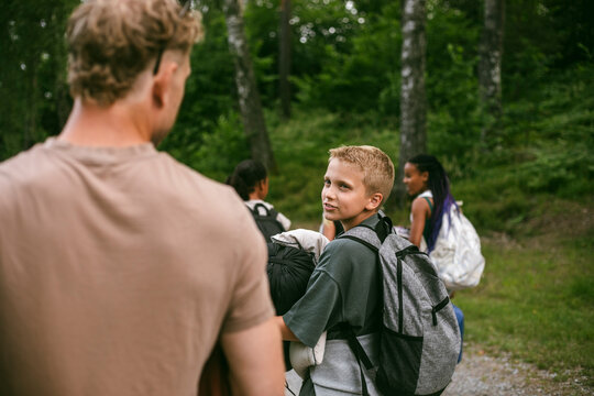 Boy talking to his camp counselor while walking on path at summer camp