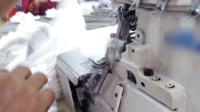 Worker Operating Industrial Overlock Machine in Clothing Manufacturing Factory.