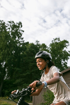 Smiling girl wearing helmet while riding mountain bike at summer camp