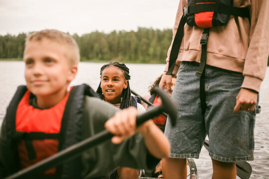 Children sitting in canoe and preparing to paddle across lake at summer camp
