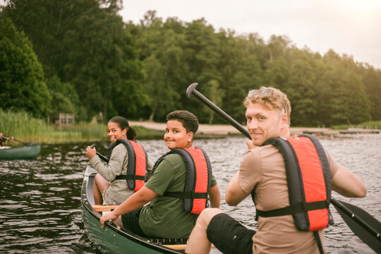 Children and counselor looking over shoulder during canoeing activity at summer camp