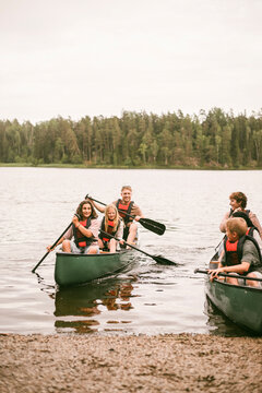 Group of children wearing life jackets while enjoying boating adventure in lake during summer camp