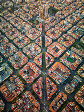 Aerial view of Sagrada Familia surrounded by the dense grid of historic city blocks and terracotta rooftops in the Eixample district, Barcelona, Catalonia, Spain.