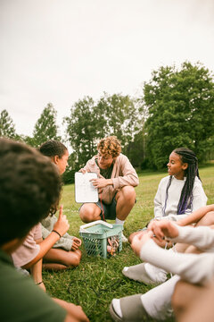Female team leader teaching navigation skills to kids during outdoor activity at summer camp