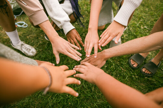 High angle view of children and their counselors stacking hands during activity at summer camp