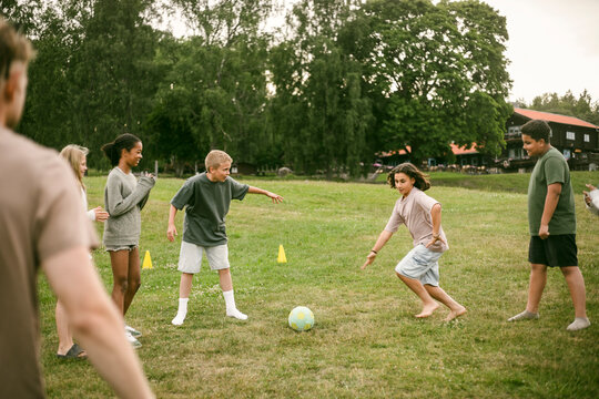 Group of children playing fun game of soccer on grass at park