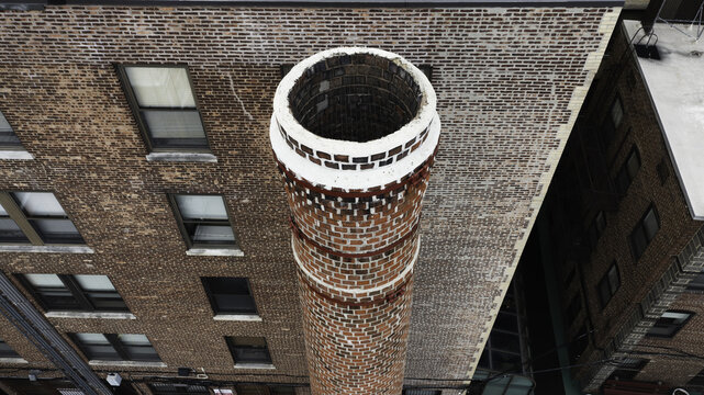 Aerial view of a tall brick chimney rising above a historic building with multiple windows in Summit, New Jersey, United States.