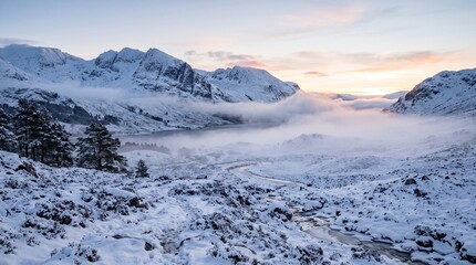 Obraz premium Snow covered Scottish Highlands landscape at sunrise with mist rolling over a loch and mountains