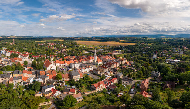 Aerial view of the historic town of Gryfow Slaski with red-tiled rooftops, a central church spire, and green landscapes under a blue sky in Gryfow Slaski, Lower Silesia, Poland.