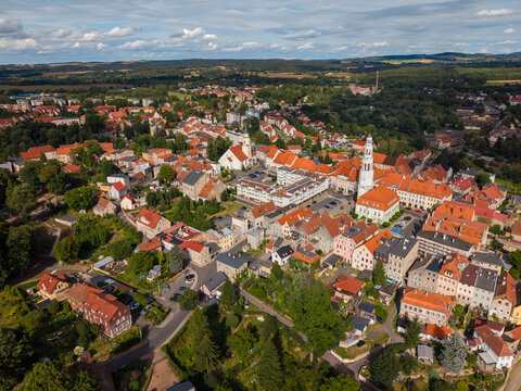 Aerial view of the historic town of Gryfow Slaski featuring a central square, church towers, and dense red-tiled rooftops surrounded by lush greenery in Gryfow Slaski, Lower Silesia, Poland.