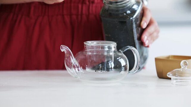 Woman Making Tea In A Clear Teapot In The Kitchen, Close-Up