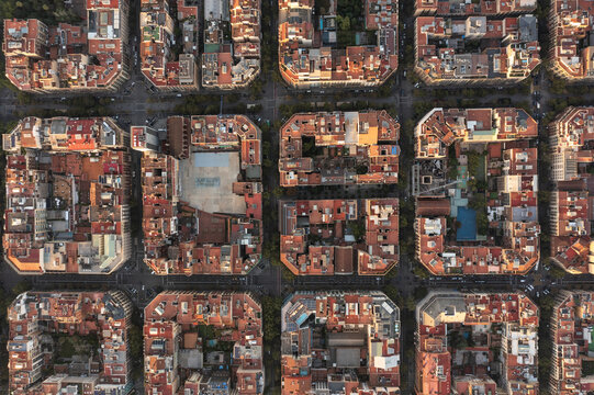 Aerial view of the Eixample district in Barcelona, featuring the iconic grid layout of city blocks with terracotta rooftops, courtyards, and narrow streets in Barcelona, Catalonia, Spain.