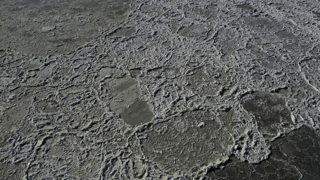 Aerial view of ice floes floating on the water surface in the winter, creating a textured pattern of frozen fragments in Highlands, New Jersey, United States.