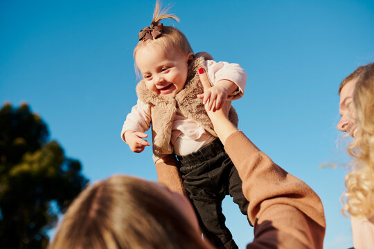 Blue sky frames a joyful, smiling child being held aloft