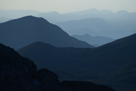 Misty Peaks Rise Behind a Green Forested Ridge in a Peaceful Landscape