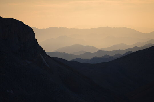Layered Mountain Ridges Fade into Morning Haze Above a Dark Conifer Forest