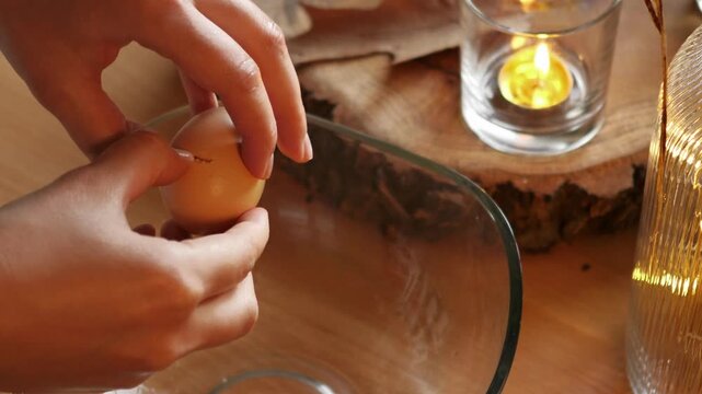Cracking raw egg and separating egg yolk from egg white into glass bowl