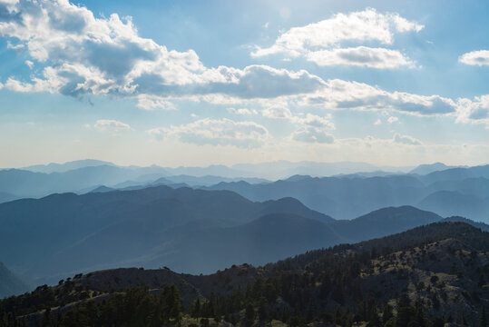 Evergreen Forest Covers a Rocky Ridge Above Hazy Mountain Layers