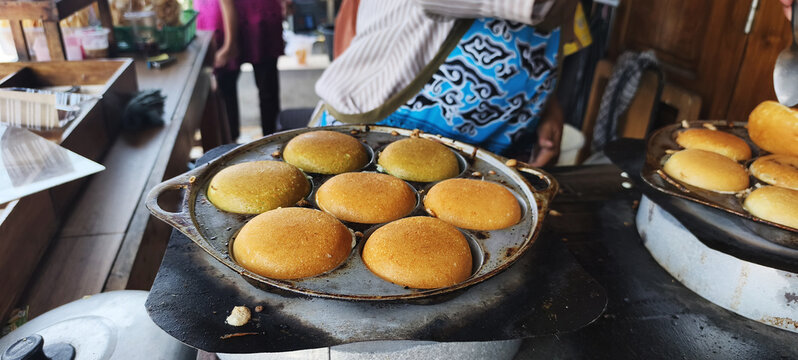 The process of making *Apem* cakes: frying and flipping the cakes in the pan. *Apem* is a traditional Javanese snack made from rice flour.
