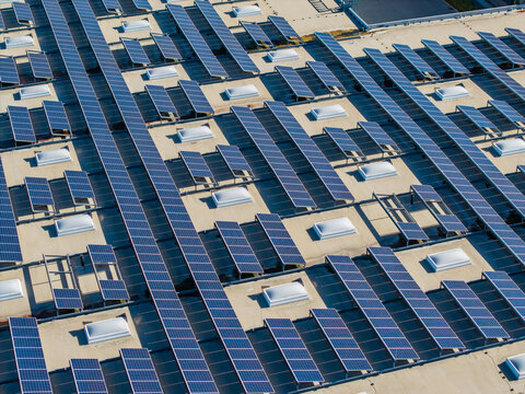 Aerial view of Logistikzentrum Allhaming featuring extensive rows of solar panels and numerous skylights on a large industrial rooftop in Allhaming, Oberosterreich, Austria.