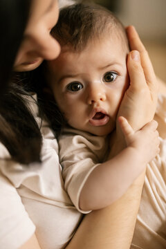 Baby looks surprised as parent holds them close in warm embrace during quiet home moment