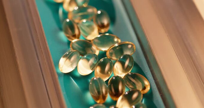 Tracking shot of softgel capsules moving along production line packaging pharm machine.