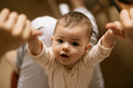 Tiny baby reaches out arms wide eyes bright smiling in warm cozy home light