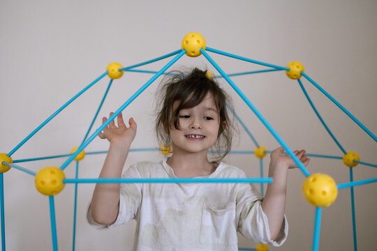 Young girl smiles inside colorful play structure enjoying indoor fun with bright cheerful energy