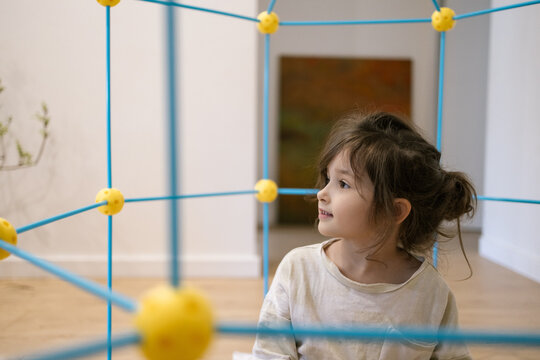 Young girl smiles while playing with colorful cube toy in bright modern room