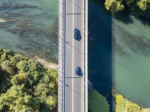 Aerial view of Ura e re e Bunes with cars driving across the bridge over the river surrounded by lush green trees in Shkoder, Qarku i Shkodres, Albania.