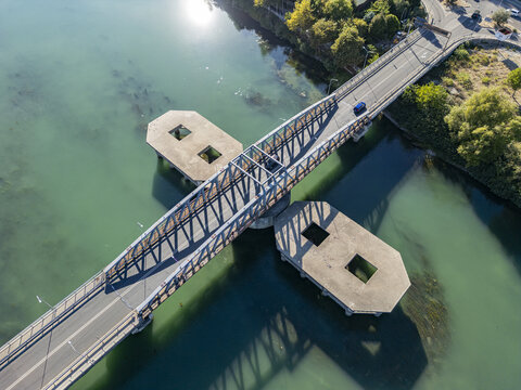 Aerial view of Ura e re e Bunes bridge spanning the turquoise waters of the Buna River with concrete support structures and surrounding greenery in Shkoder, Qarku i Shkodres, Albania.