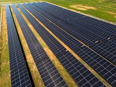 Aerial view of a large solar farm with rows of photovoltaic panels installed on open land in Ladismith, Western Cape, South Africa.