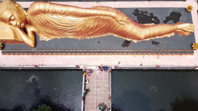 Aerial top down reveal of the giant golden Reclining Buddha statue at Maha Vihara Mojopahit in Trowulan, East Java, Indonesia.