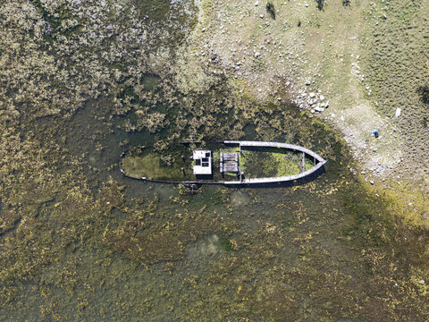 Aerial view of the sunken boat Anija e mbytur resting in the shallow, algae-covered waters near the shore in Shiroka, Shkoder County, Albania.