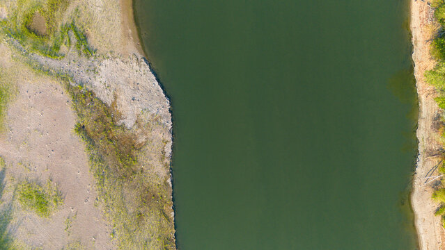 Aerial view of the Po River showing low water levels and exposed riverbed sediments due to summer drought in Castelvetro Piacentino, Emilia-Romagna, Italy.