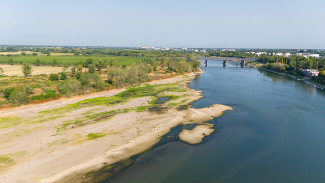 Aerial view of the Po River with low water levels and exposed riverbed sediments caused by a summer heatwave and drought near Castelvetro Piacentino, Emilia-Romagna, Italy.