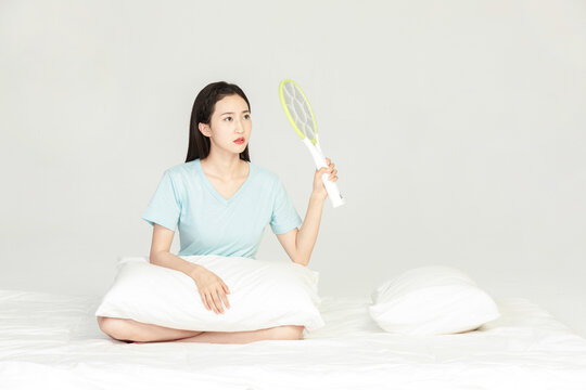 Woman Sitting on Bed Holding Electric Mosquito Swatter