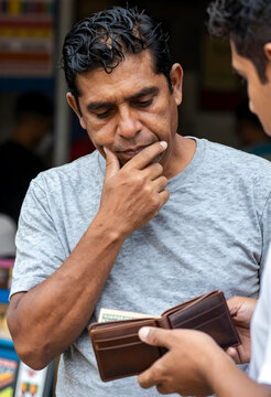 Financial struggle and poverty, man looking at empty wallet with concern and stress about inflation and cost of living in a difficult economic situation