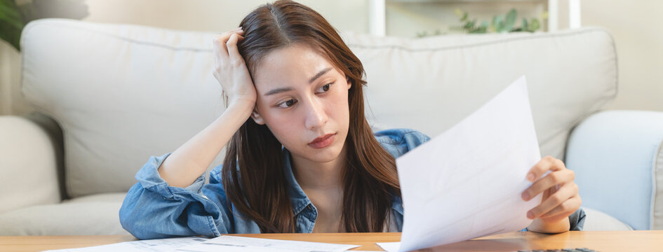 young asian woman cover her head after stressed with monthly bill expenses and credit card debt.