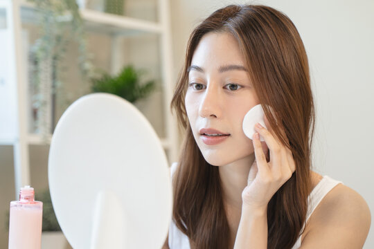 Young asian woman applying moisturizer on face after use toner cleansing remove cosmetic.
