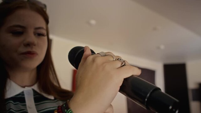 Caucasian teenage girl inserting microphone into stand holder during music rehearsal. Footage suited for vocal training promos, music education ads and youth talent campaigns
