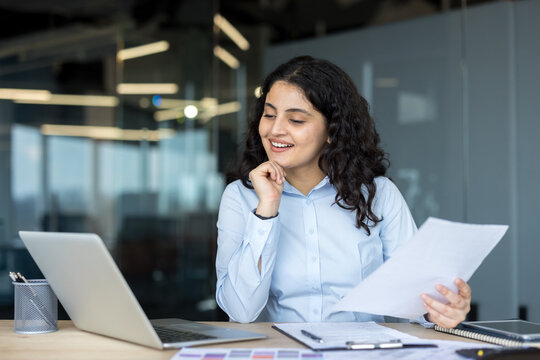 Young businesswoman reading document and smiling in office