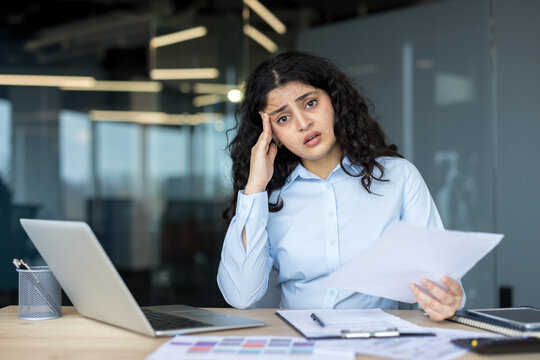 Young businesswoman experiencing stress and headache at office desk
