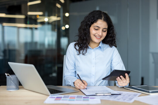 Young businesswoman calculating finances and writing on documents