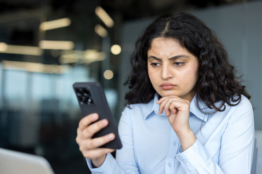Woman feeling concerned reading message on smartphone screen